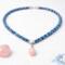 Flat lay of Bead & Braid Collective Kumihimo necklace with rose quartz pendant, blue glass beads and silver findings